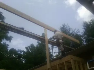 Carpenter setting a ridge beam over a new addition frame — Ice Dam Removal by Roofing Brothers in Moravia