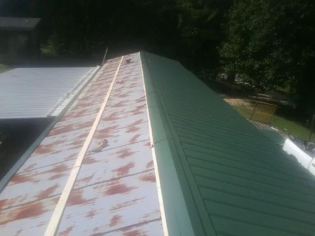 Old rusted panels beside newly installed green metal roofing — Wind Damage Roof Repair by Roofing Brothers in Moravia