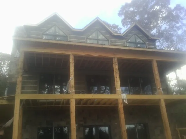 Dormers and porch framing on a large log home under construction — Roof Coating work by our crew in Moravia